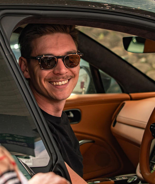 John Whittle smiling behind the wheel of an Aston Martin